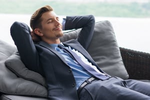 smiling-man-with-hands-head-dozing-couch